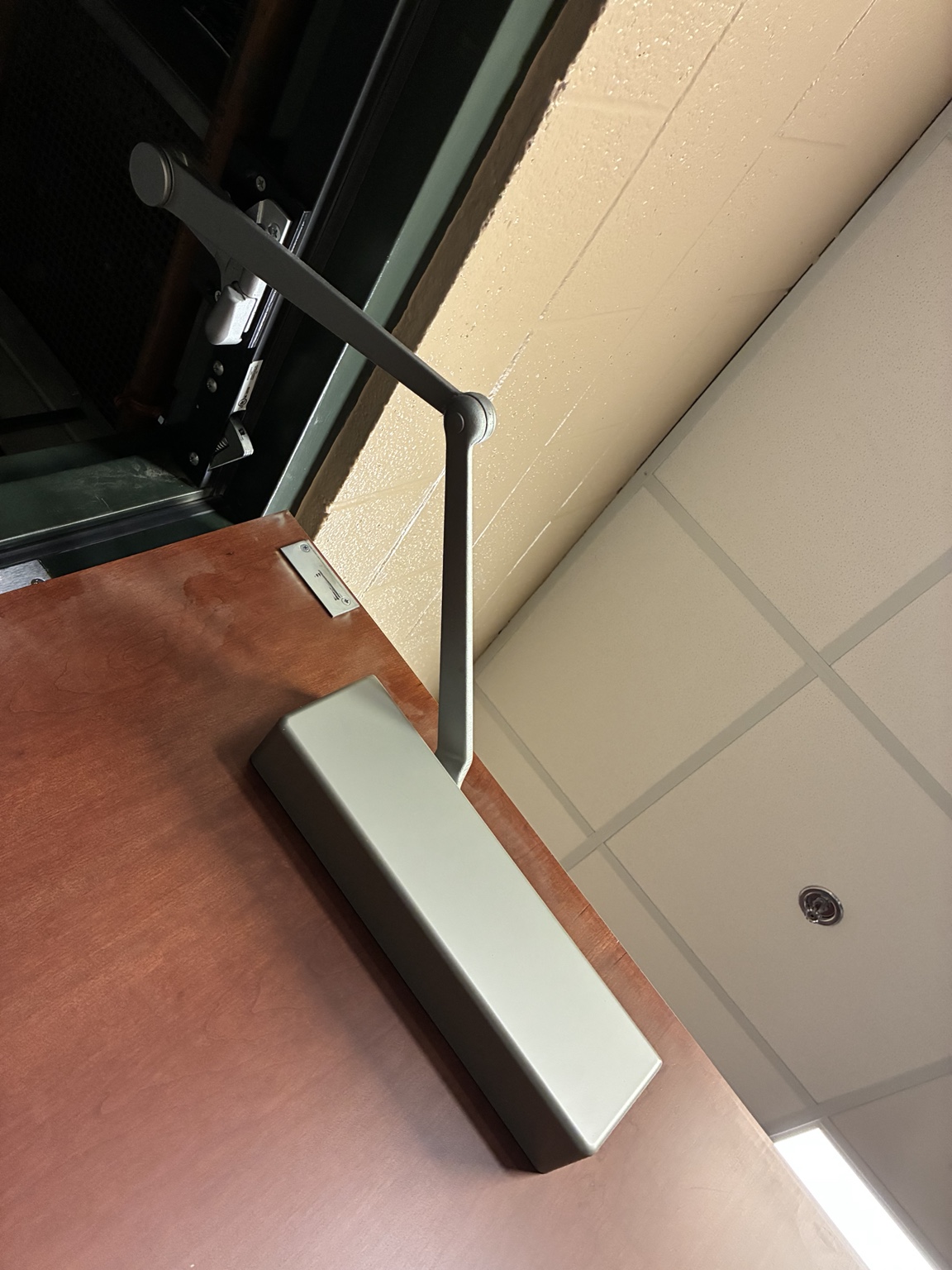 Surface-mounted commercial hydraulic door closer with articulated arm on a wood door